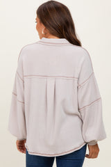 woman wearing a light pink maternity top with a relaxed fit and balloon sleeves, showing the back view