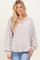 woman wearing a light beige oversized pullover top with a henley neckline and a front pocket, styled with rolled sleeves
