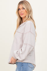 woman wearing a light beige striped oversized sweatshirt with pockets and long sleeves