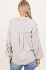 woman wearing a light taupe striped oversized sweater with balloon sleeves and a relaxed fit