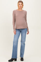 woman wearing a taupe long sleeve maternity top and blue flared jeans, showing her baby bump