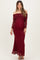 woman wearing a burgundy off-the-shoulder maternity gown with long sheer sleeves and a fitted silhouette, showcasing her baby bump