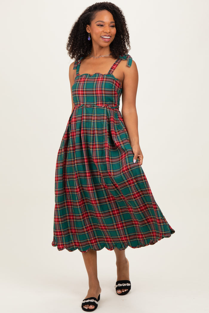woman wearing a green plaid midi dress with scalloped details and adjustable straps