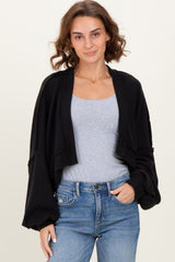 woman wearing a black cropped ribbed cardigan over a grey tank top and high-waisted jeans