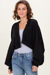woman wearing a black cropped cardigan with balloon sleeves over a gray top and blue jeans