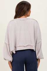 woman wearing a light pink cropped maternity sweatshirt with oversized sleeves and a ribbed texture, showing her back