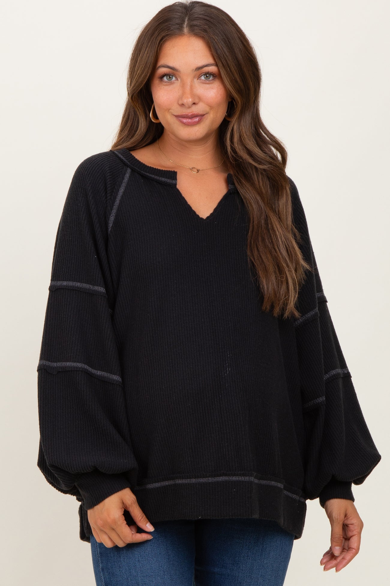 woman wearing a black maternity sweater with a v-neck and balloon sleeves, showing a relaxed fit