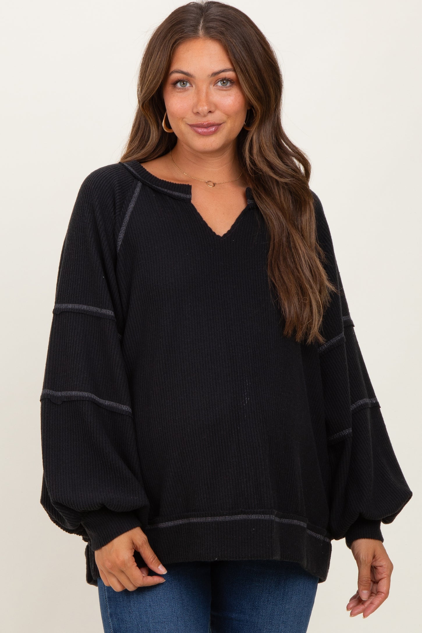 woman wearing a black maternity sweater with a v-neck and balloon sleeves, showing a relaxed fit