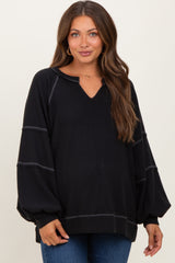 woman wearing a black maternity sweater with a v-neck and balloon sleeves, showing a relaxed fit