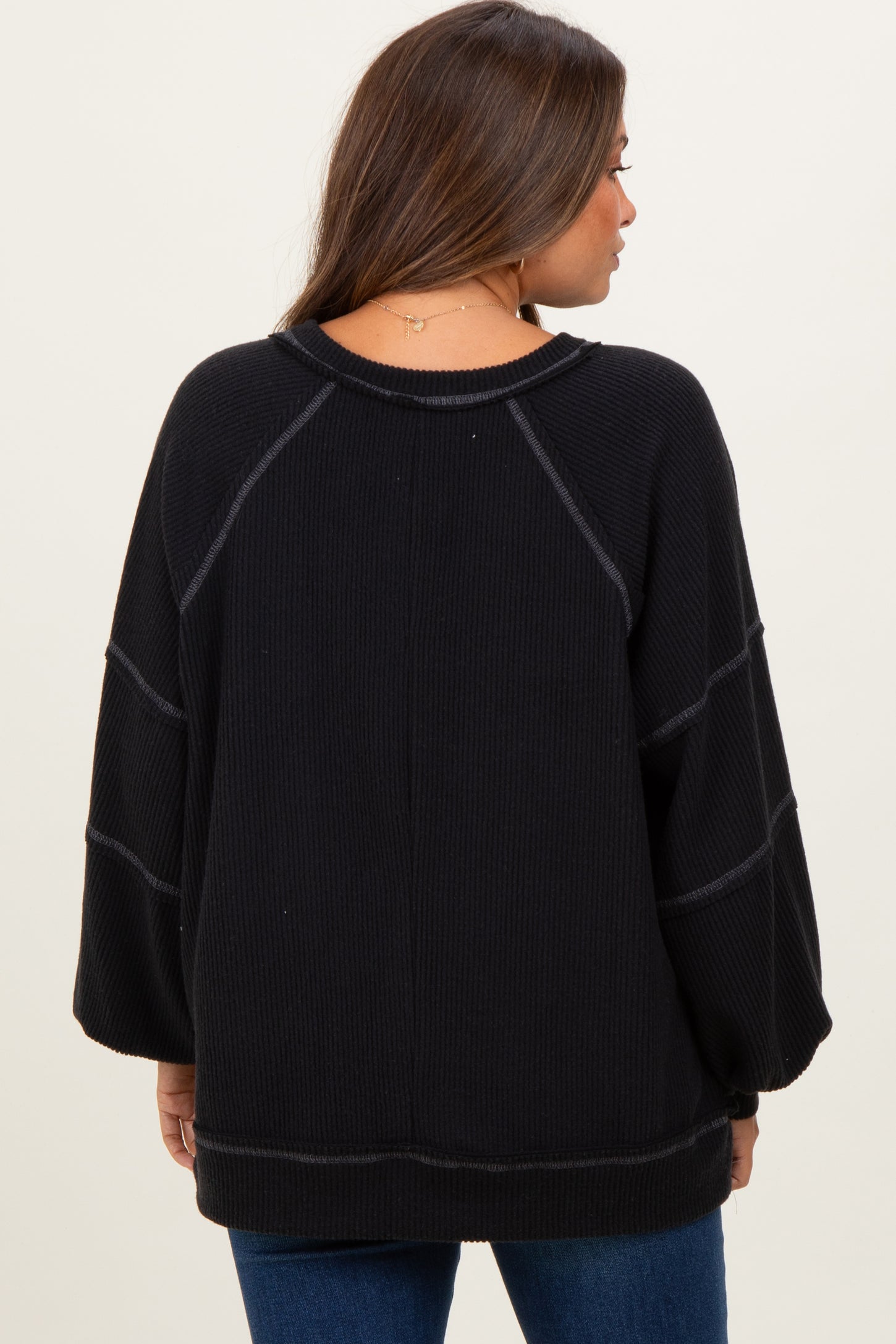 woman wearing a black maternity sweater with a relaxed fit and ribbed texture, shown from the back