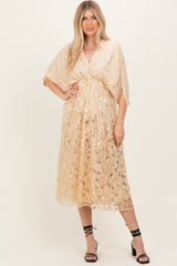 woman wearing a beige midi dress with floral sequin details and short kimono sleeves, styled with strappy black heels