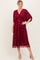 woman wearing a deep red embroidered midi dress with short sleeves and a wrap silhouette, styled with nude heels