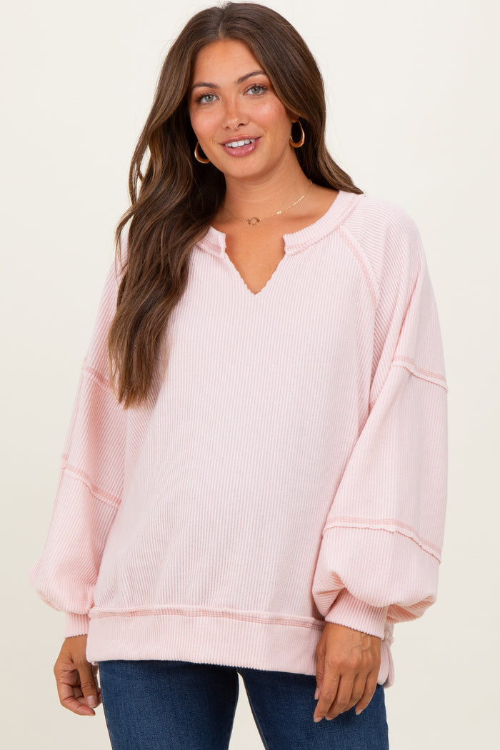 woman wearing a light pink maternity pullover with a v-neck and balloon sleeves