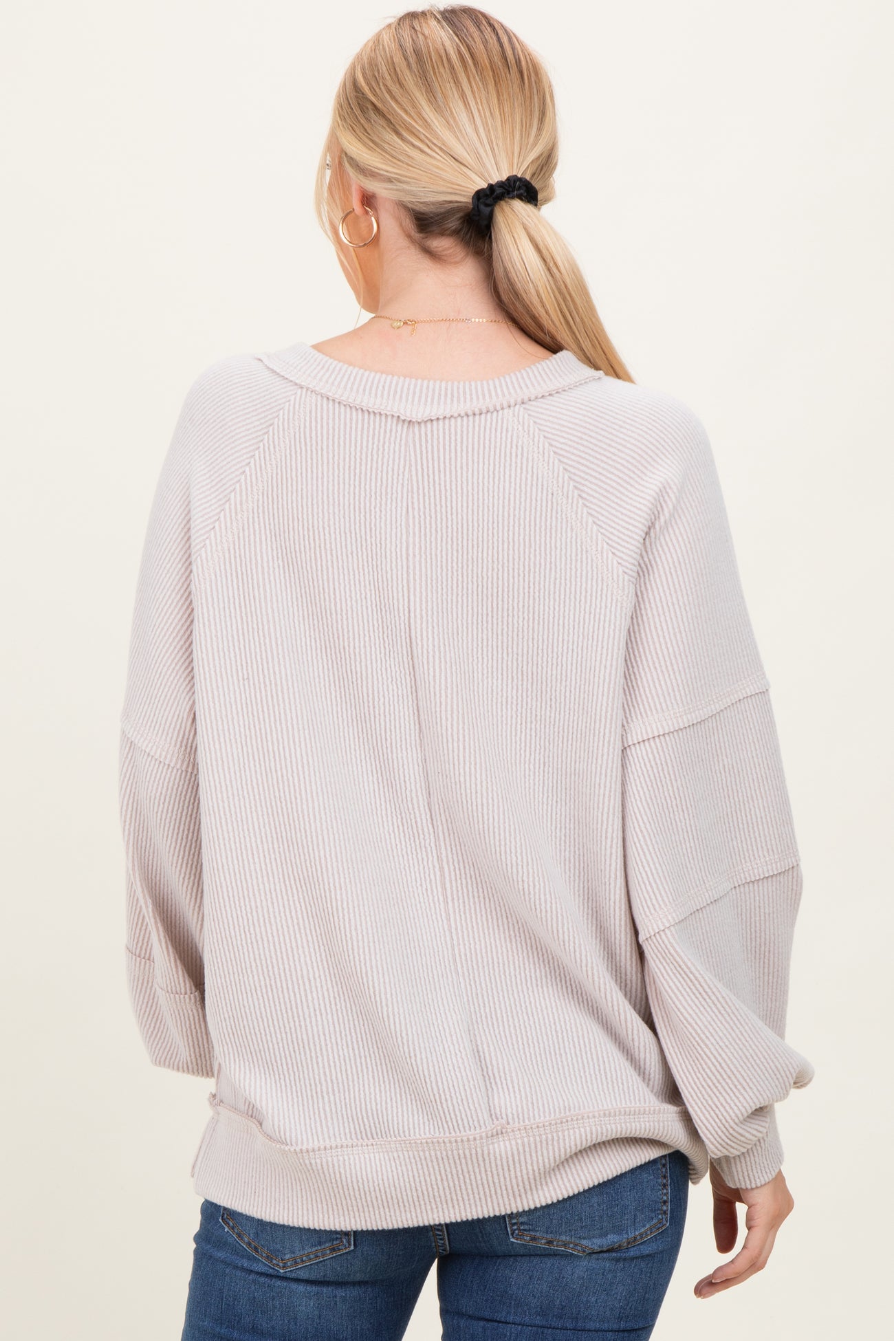 woman wearing a light beige oversized ribbed sweater with a relaxed fit and long sleeves, seen from the back
