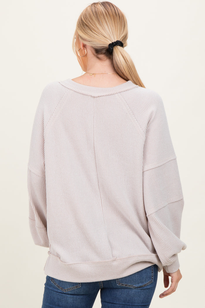 woman wearing a light beige oversized ribbed sweater with a relaxed fit and long sleeves, seen from the back