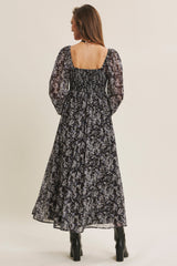 woman wearing a black floral maxi dress with puff sleeves, showcasing a smocked back detail