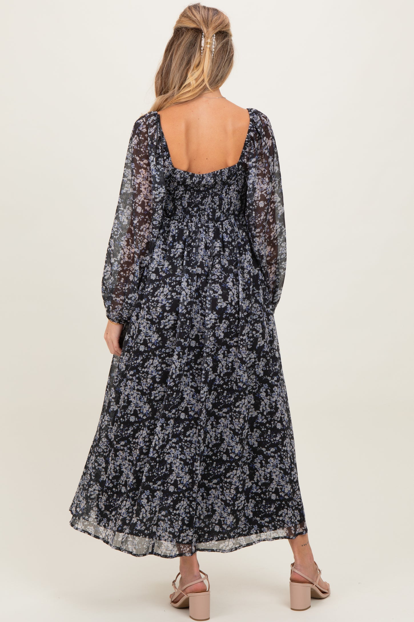 woman wearing a navy blue floral maternity maxi dress with long sleeves and a ruched back detail