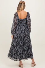 woman wearing a navy blue floral maternity maxi dress with long sleeves and a ruched back detail