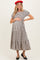woman wearing a striped black and cream maternity maxi dress and holding her baby bump