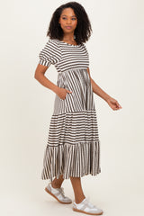 woman wearing a striped black and white maxi dress with short puff sleeves and pockets, paired with silver sneakers