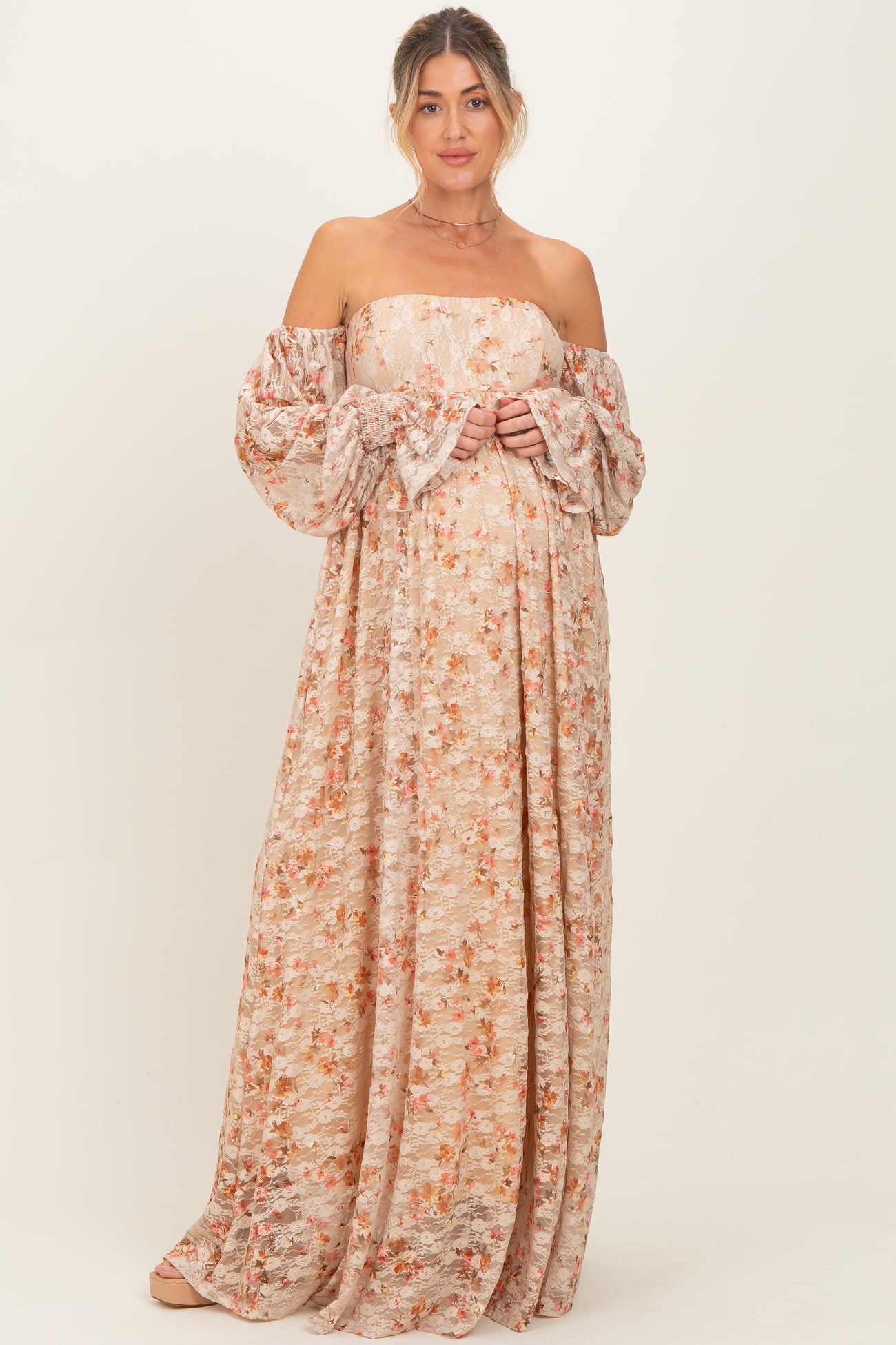 woman wearing a floral off-the-shoulder maxi dress and showing her baby bump