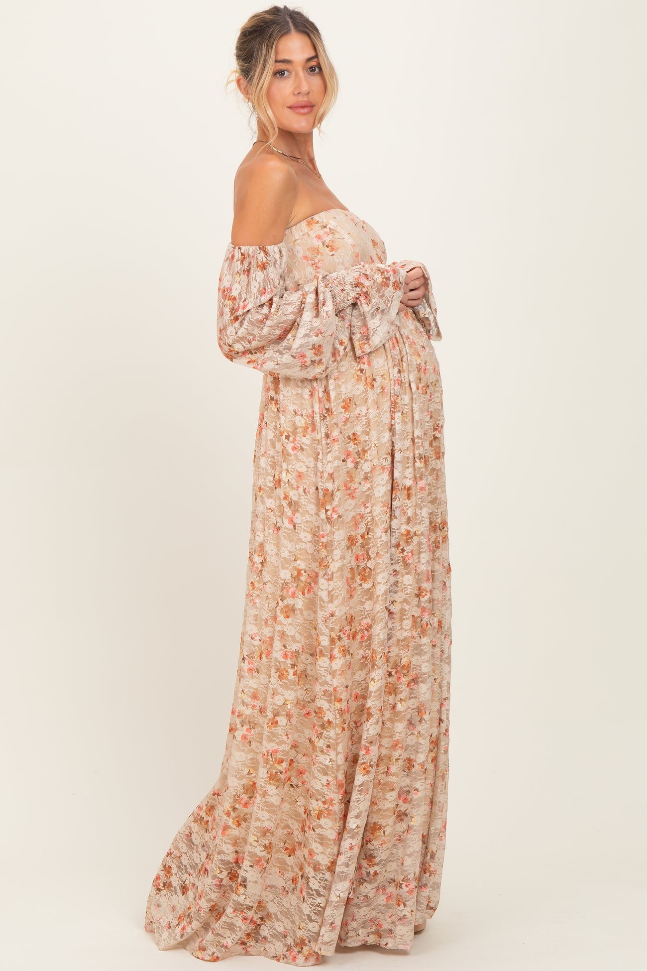 woman wearing a floral off-the-shoulder maternity maxi dress showing her baby bump