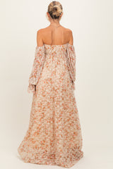 woman wearing a floral off-shoulder maternity maxi dress with long sleeves and a flowing skirt, showing a baby bump from behind