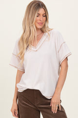 woman wearing a light beige short sleeve v-neck top with textured stripes and contrasting trim