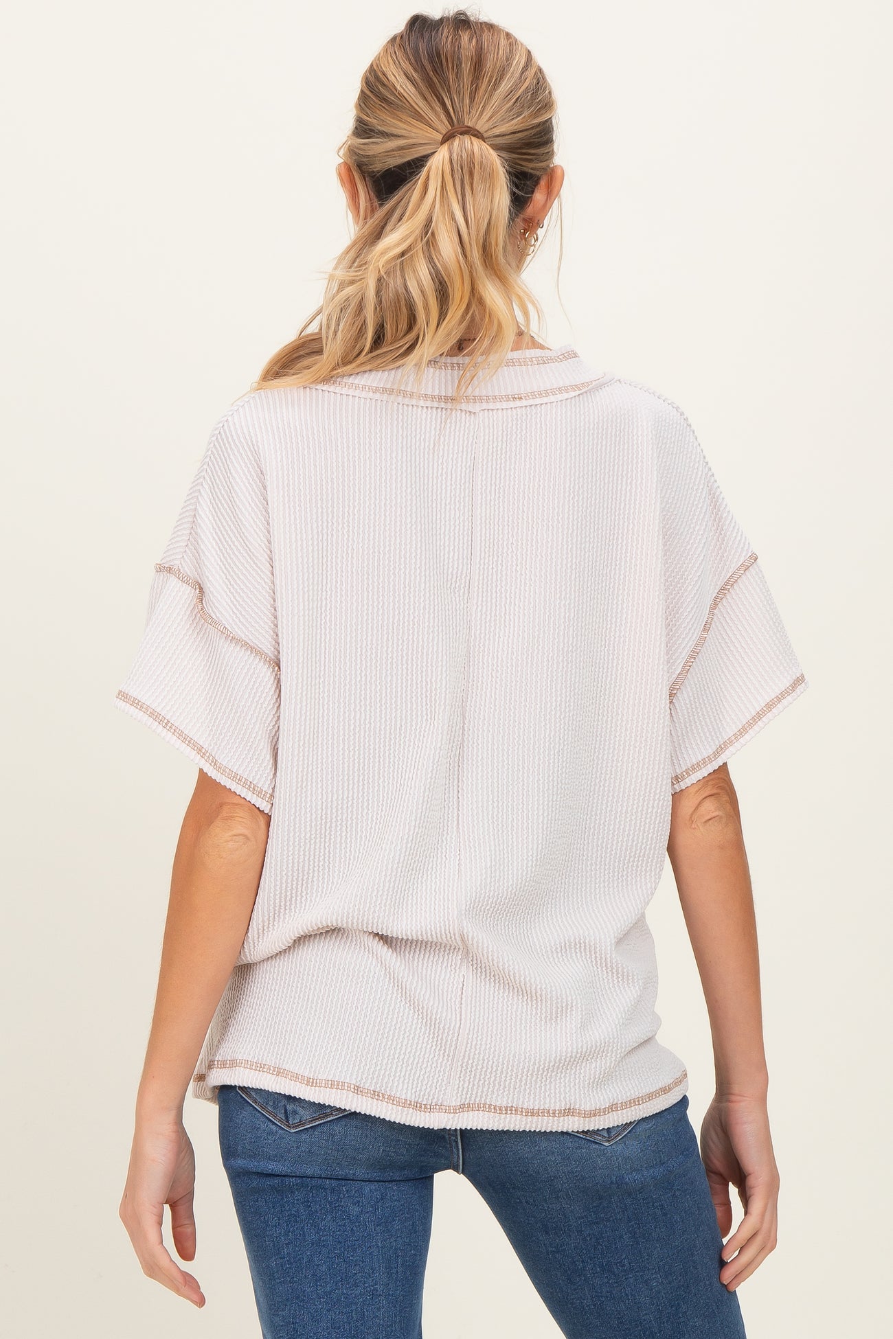 woman wearing a light pink maternity top with short sleeves and a relaxed fit, viewed from the back