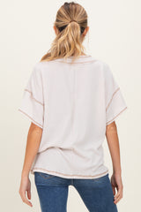 woman wearing a light pink maternity top with short sleeves and a relaxed fit, viewed from the back
