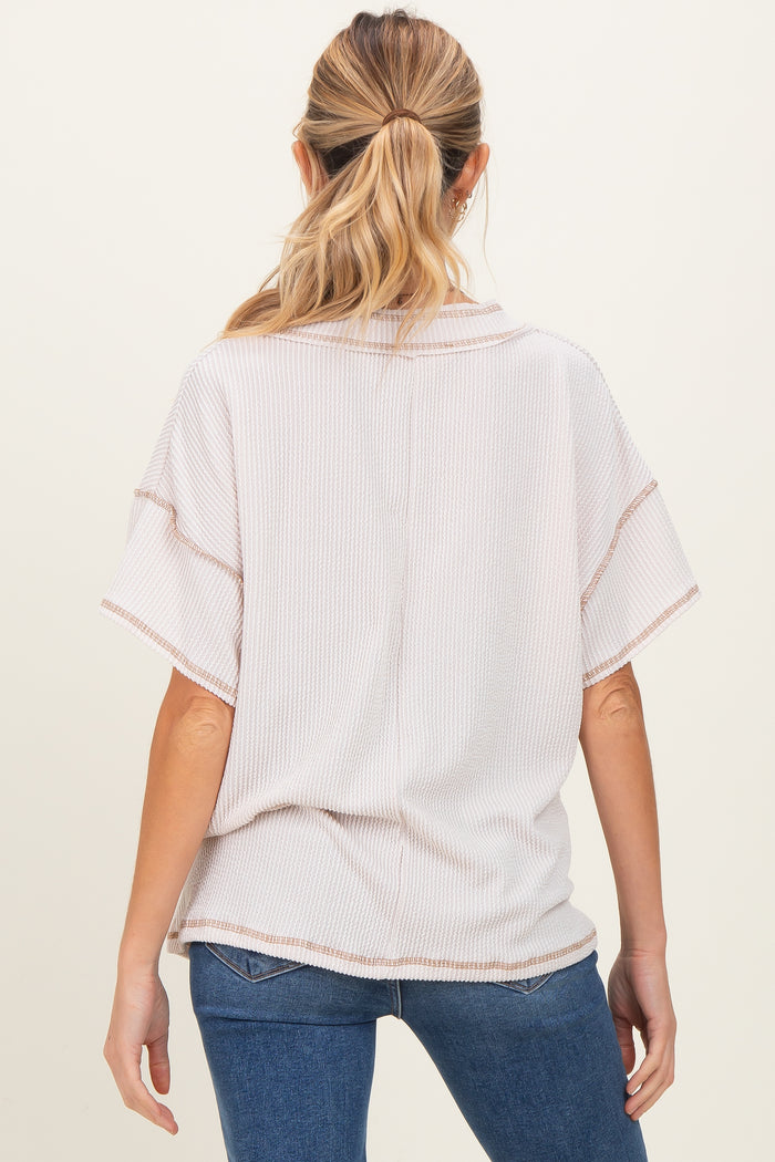 woman wearing a light pink maternity top with short sleeves and a relaxed fit, viewed from the back