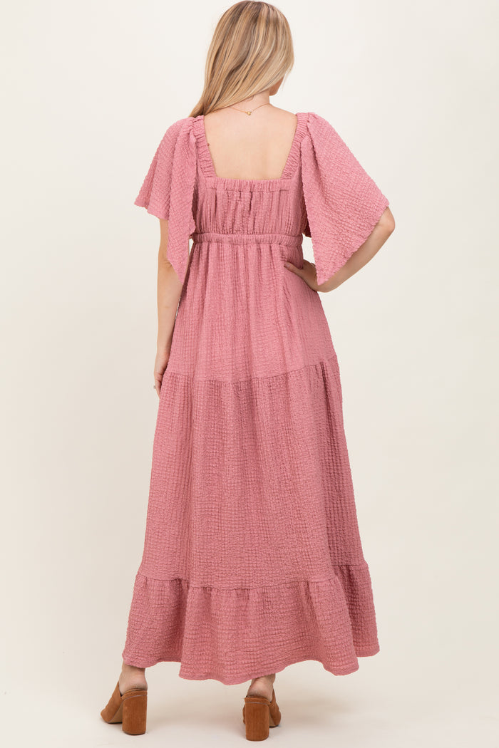 woman wearing a dusty rose maxi dress with flutter sleeves and a tiered skirt, seen from the back