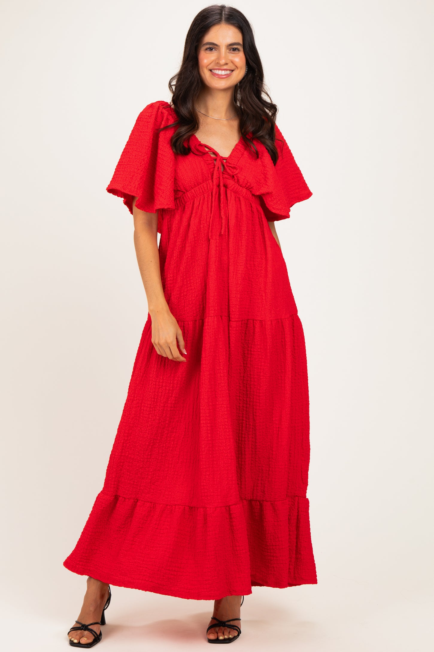 woman wearing a red tiered maxi dress with flutter sleeves and a tie front detail