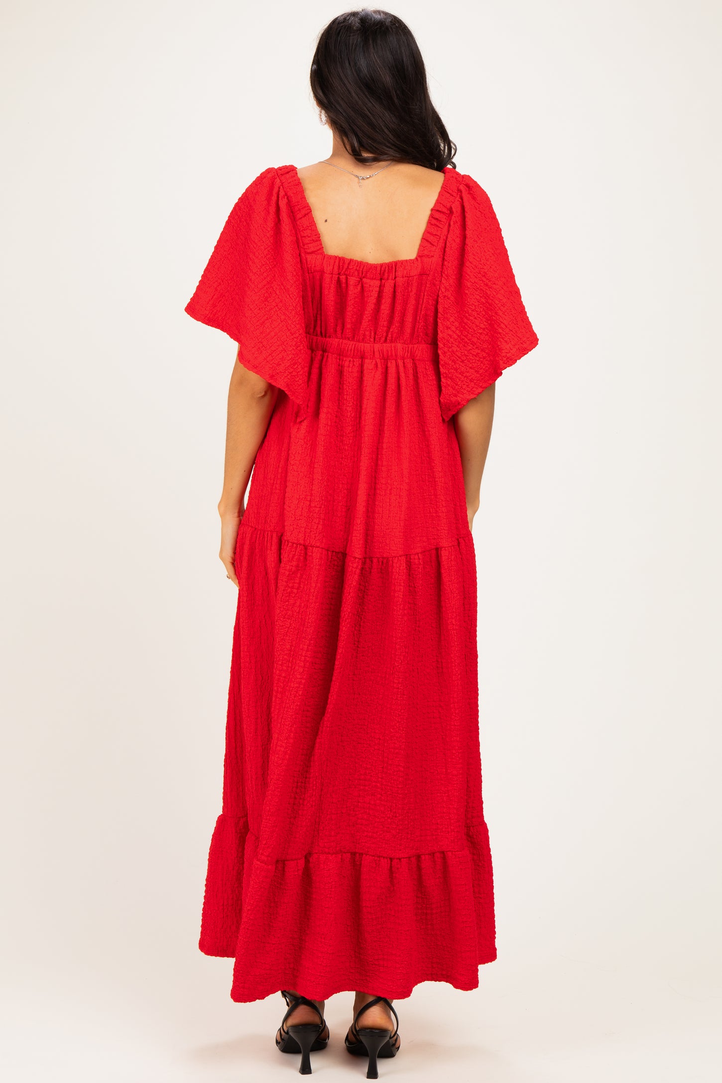 woman wearing a red tiered maxi dress with flutter sleeves and a square back neckline
