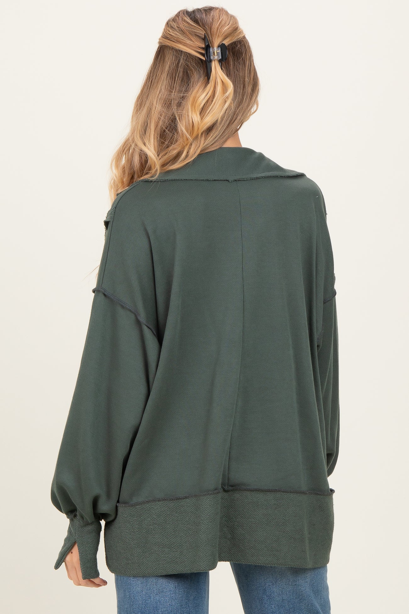 woman wearing a dark green oversized maternity top with long sleeves, shown from the back