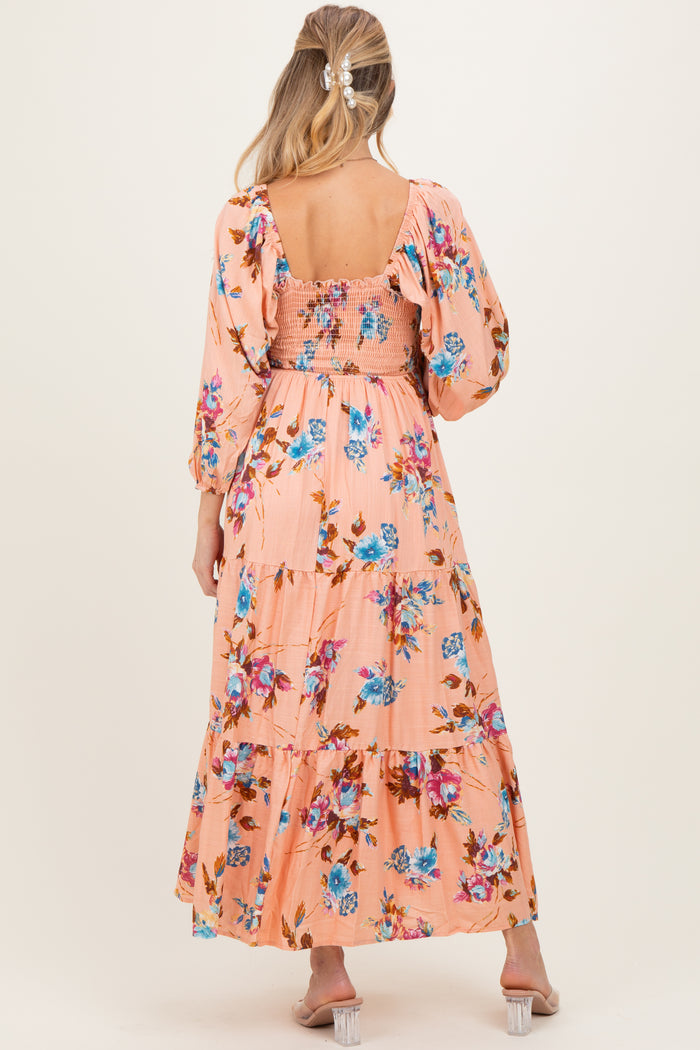 woman wearing a peach floral maternity maxi dress with puff sleeves and a smocked bodice, showing a baby bump from the back