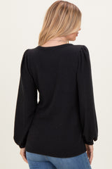 woman wearing a black ribbed sweater with puffed sleeves, viewed from the back with long blonde hair