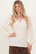 woman wearing a cream ribbed long sleeve top with a v-neck and puffed sleeves