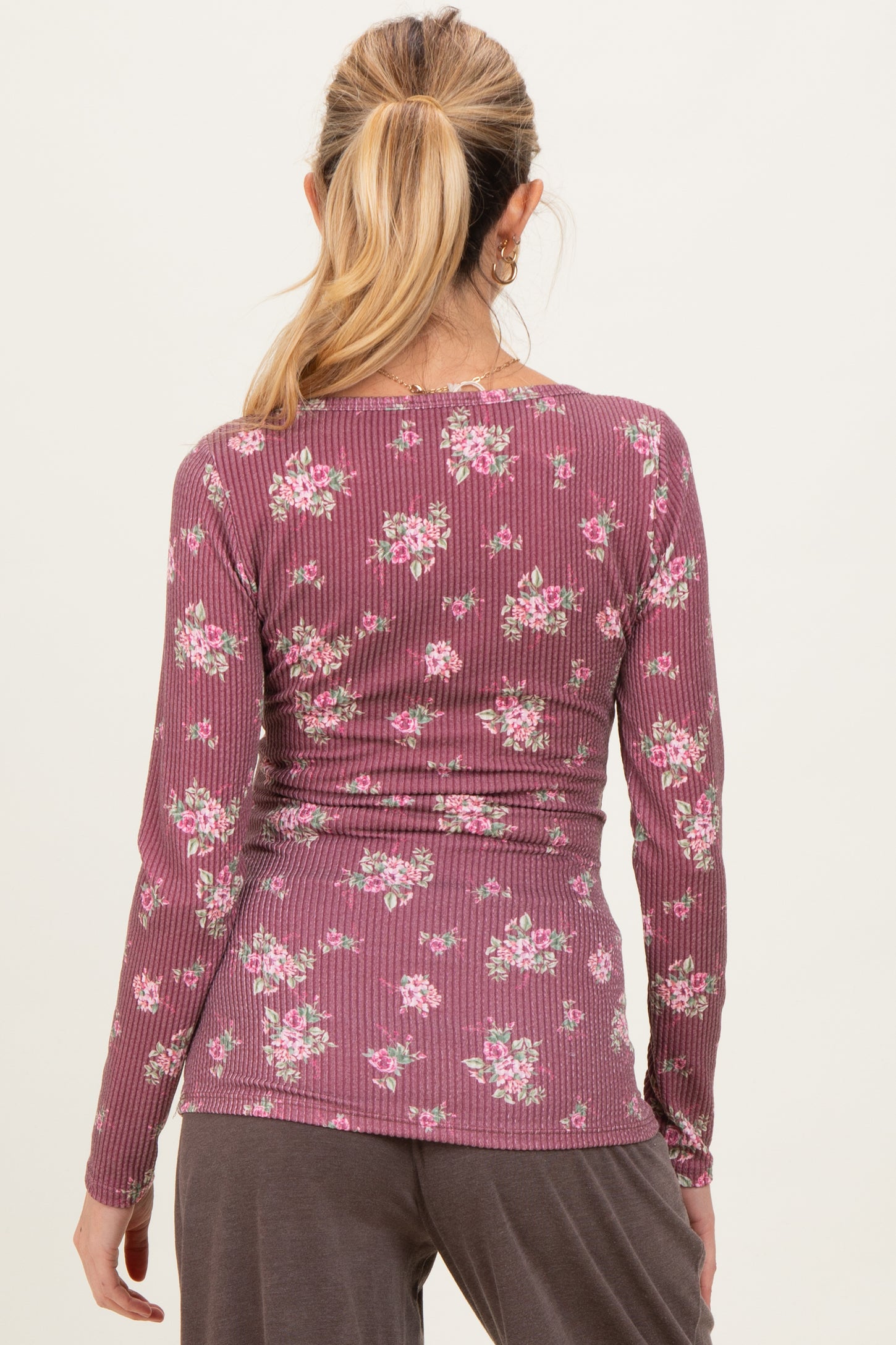 woman wearing a mauve long sleeve maternity top with a floral print, showing a fitted silhouette from the back