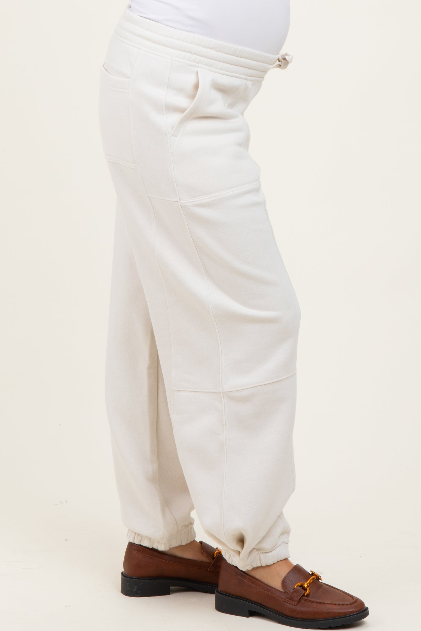 woman wearing cream-colored maternity sweatpants with elastic cuffs and side pockets