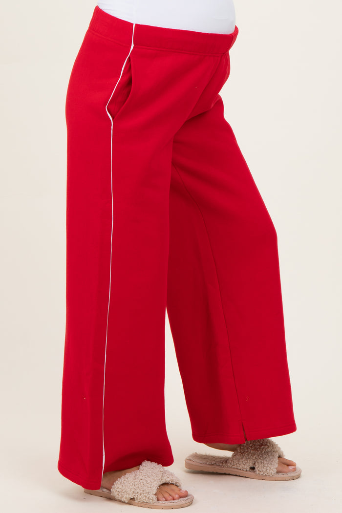 maternity wear red wide-leg pants with white piping details, model wearing them and showing a baby bump