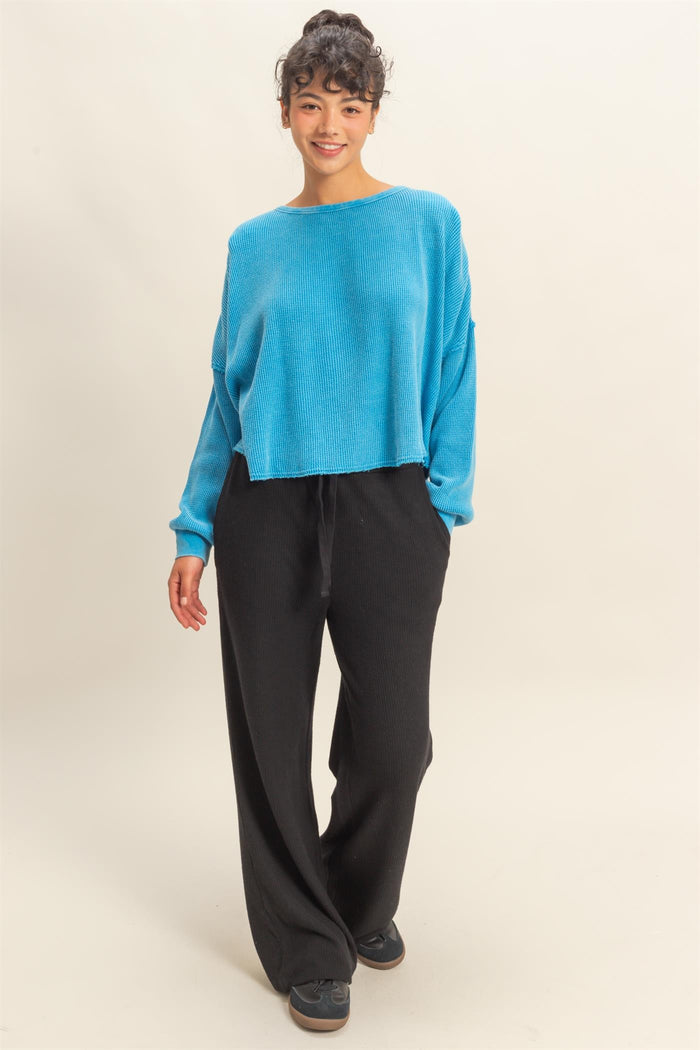woman wearing a cropped blue ribbed sweater and black wide-leg pants