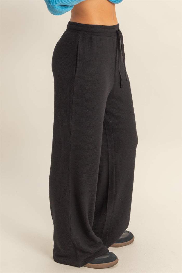 woman wearing black wide leg ribbed lounge pants with side pockets and drawstring waistband