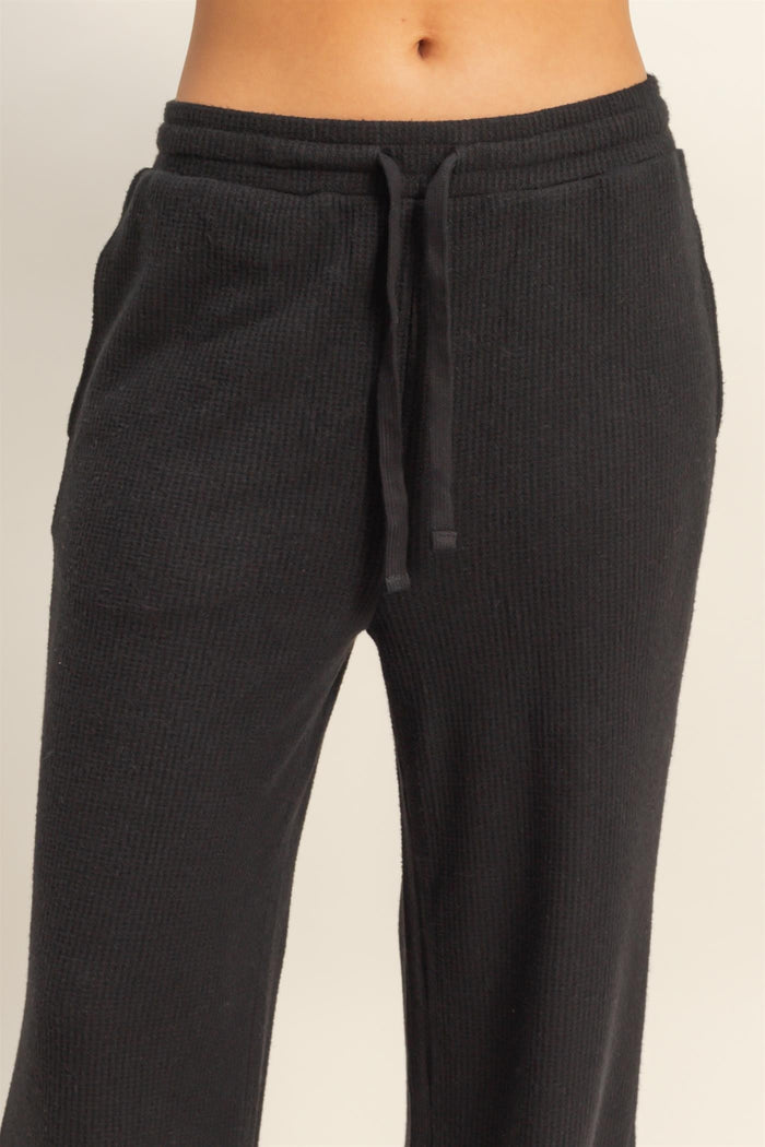 woman wearing black ribbed lounge pants with an elastic waistband and drawstring detail
