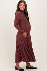 woman wearing a rust ribbed long sleeve maternity dress, gently holding her baby bump