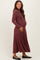 woman wearing a rust ribbed long sleeve maternity dress, gently holding her baby bump