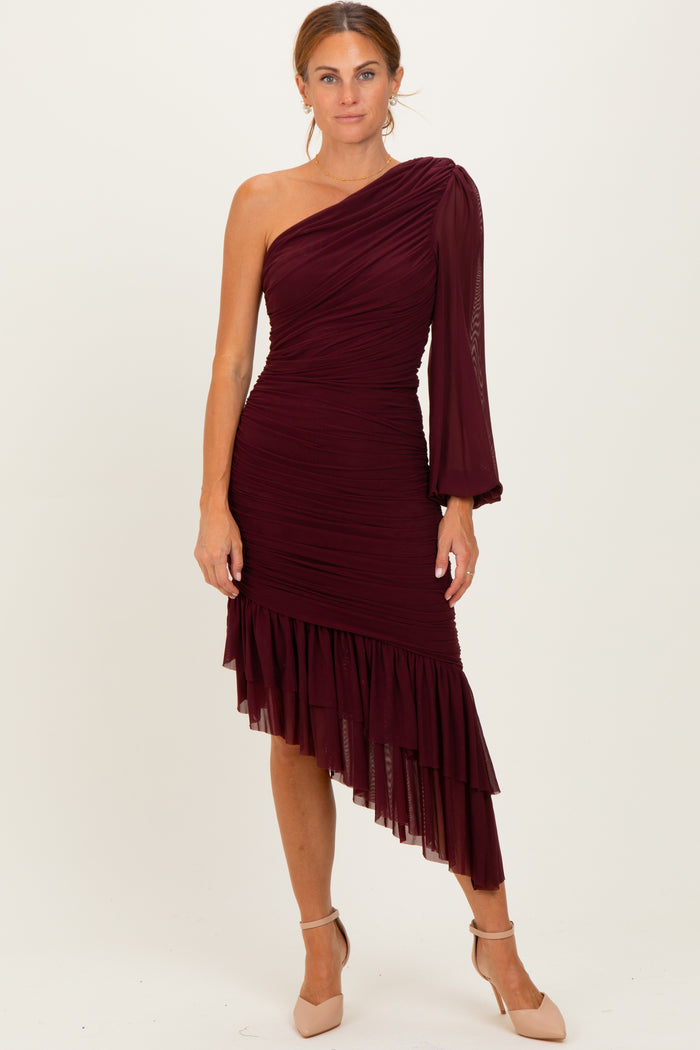 woman wearing a burgundy one-shoulder dress with ruched detailing and a layered ruffled hem