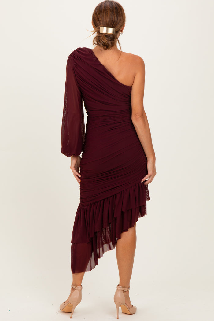 woman wearing a burgundy one-shoulder dress with ruched detailing and a layered ruffled hem