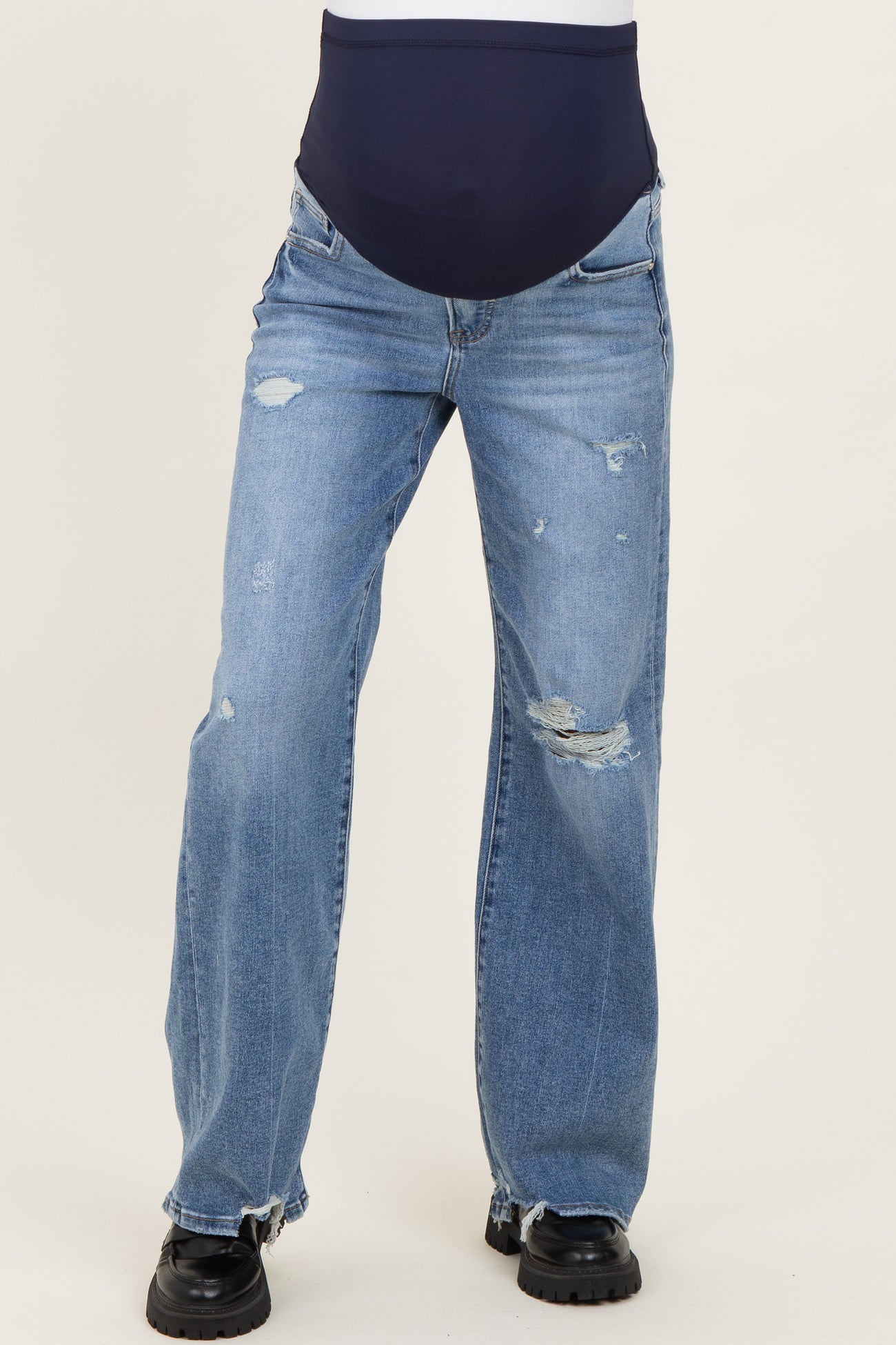 woman wearing light blue distressed maternity jeans with a dark blue over-the-bump waistband