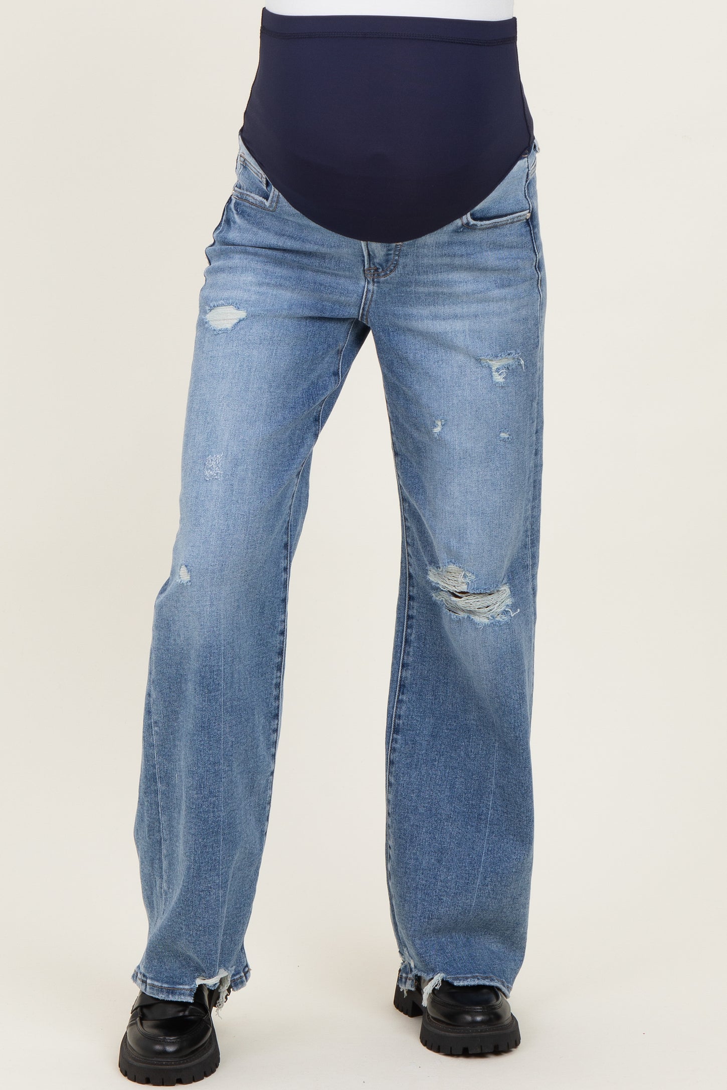 woman wearing light blue distressed maternity jeans with a dark blue over-the-bump waistband